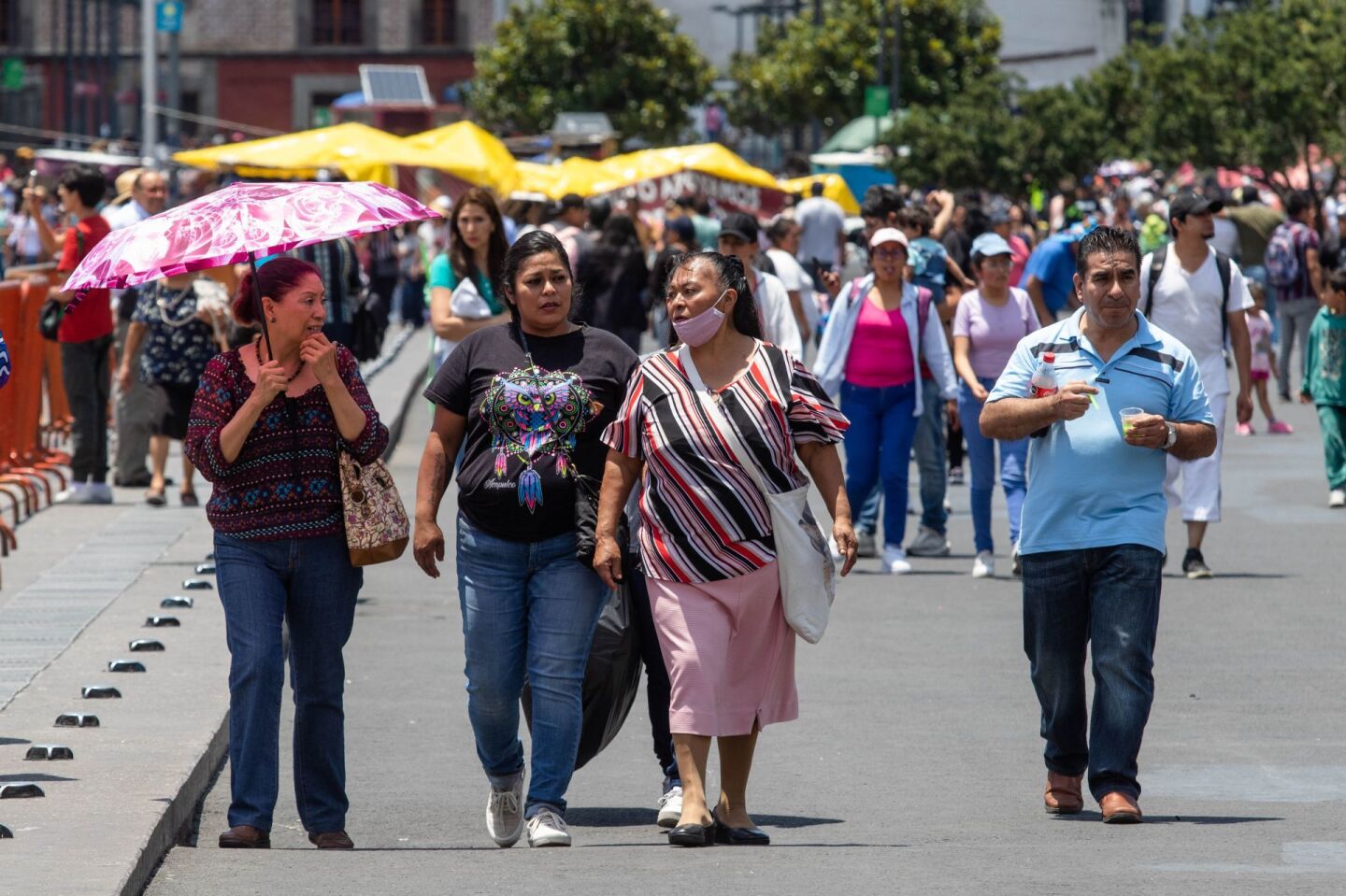 Intenso calor se registró este domingo en la capital. En la imagen paseantes con sombrilla caminan en el Zócalo.