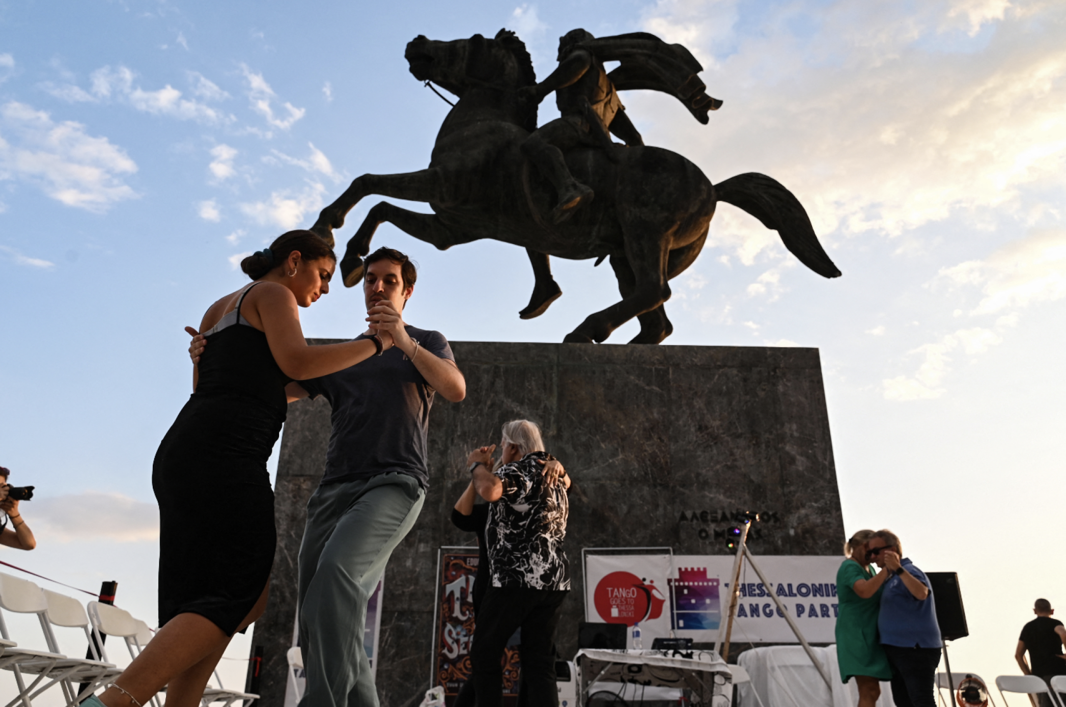 Turistas bailan tango en Grecia frente a una estatua de Alejandro Magno