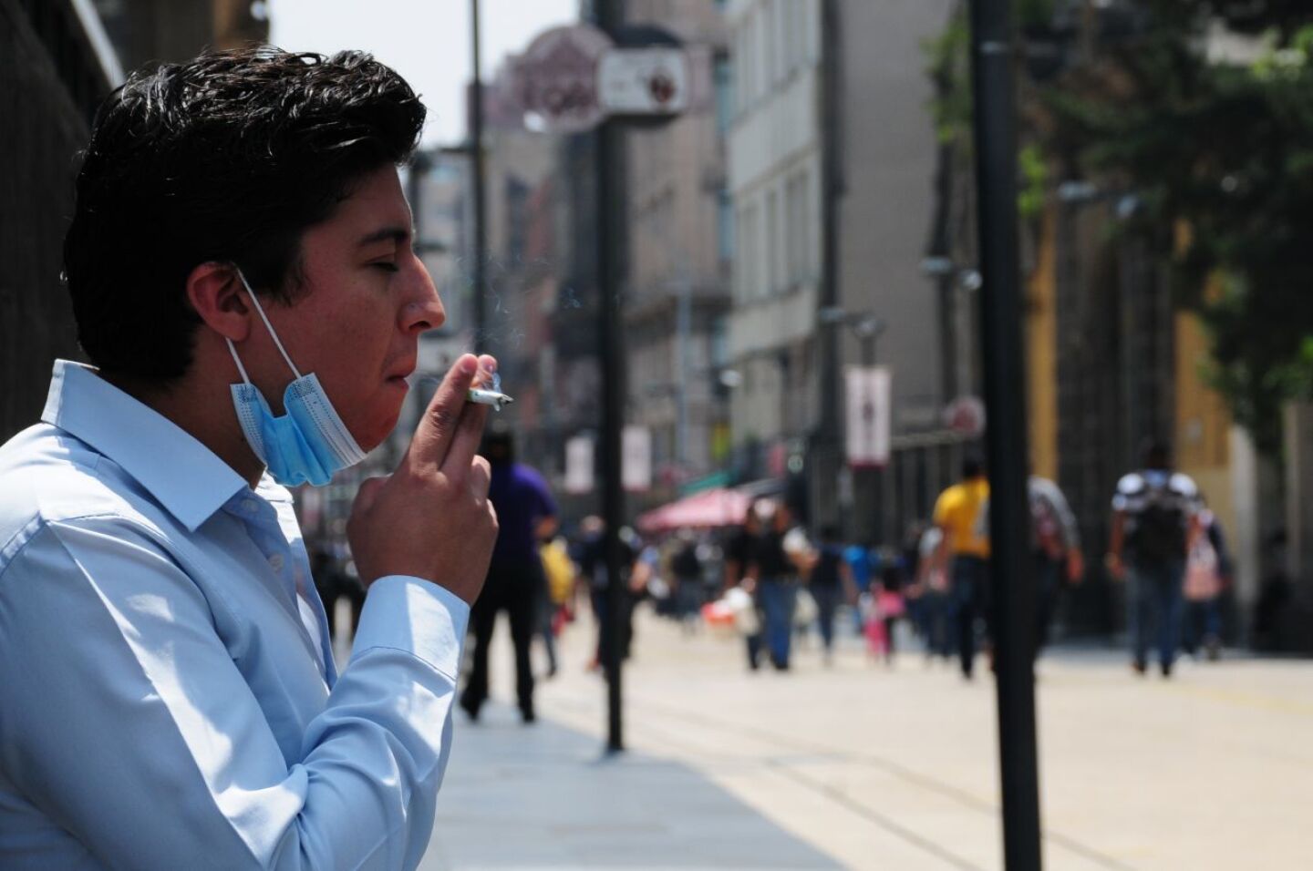 Un hombre fuma un cigarro sobre la calle de Madero.