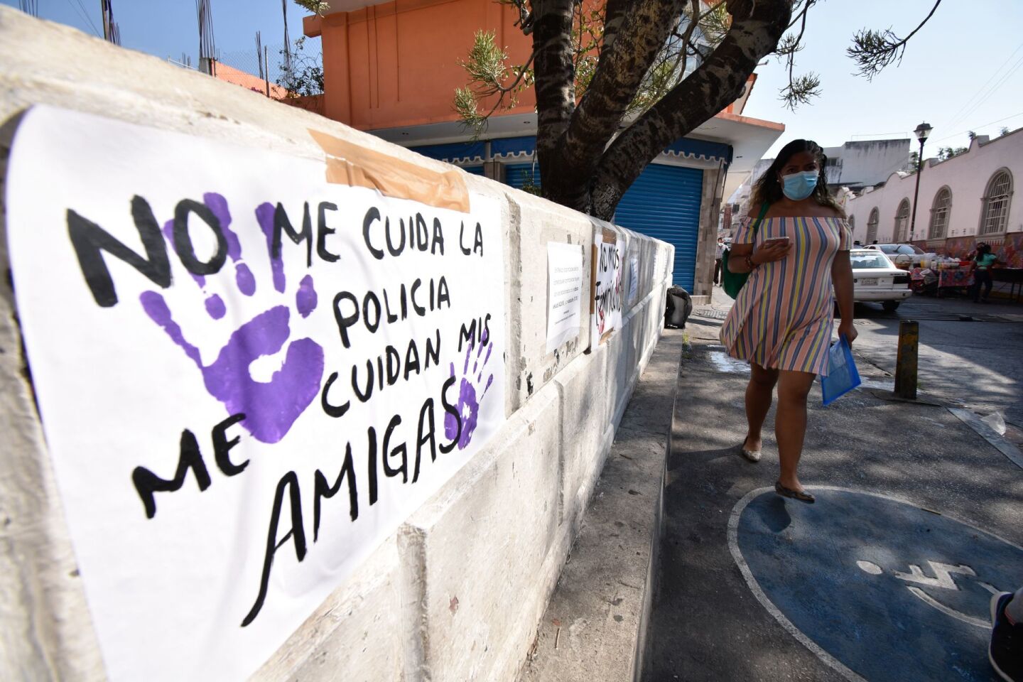 Una mujer camina frente a una pancarta que dice "no me cuida la policía me cuidan mis amigas".