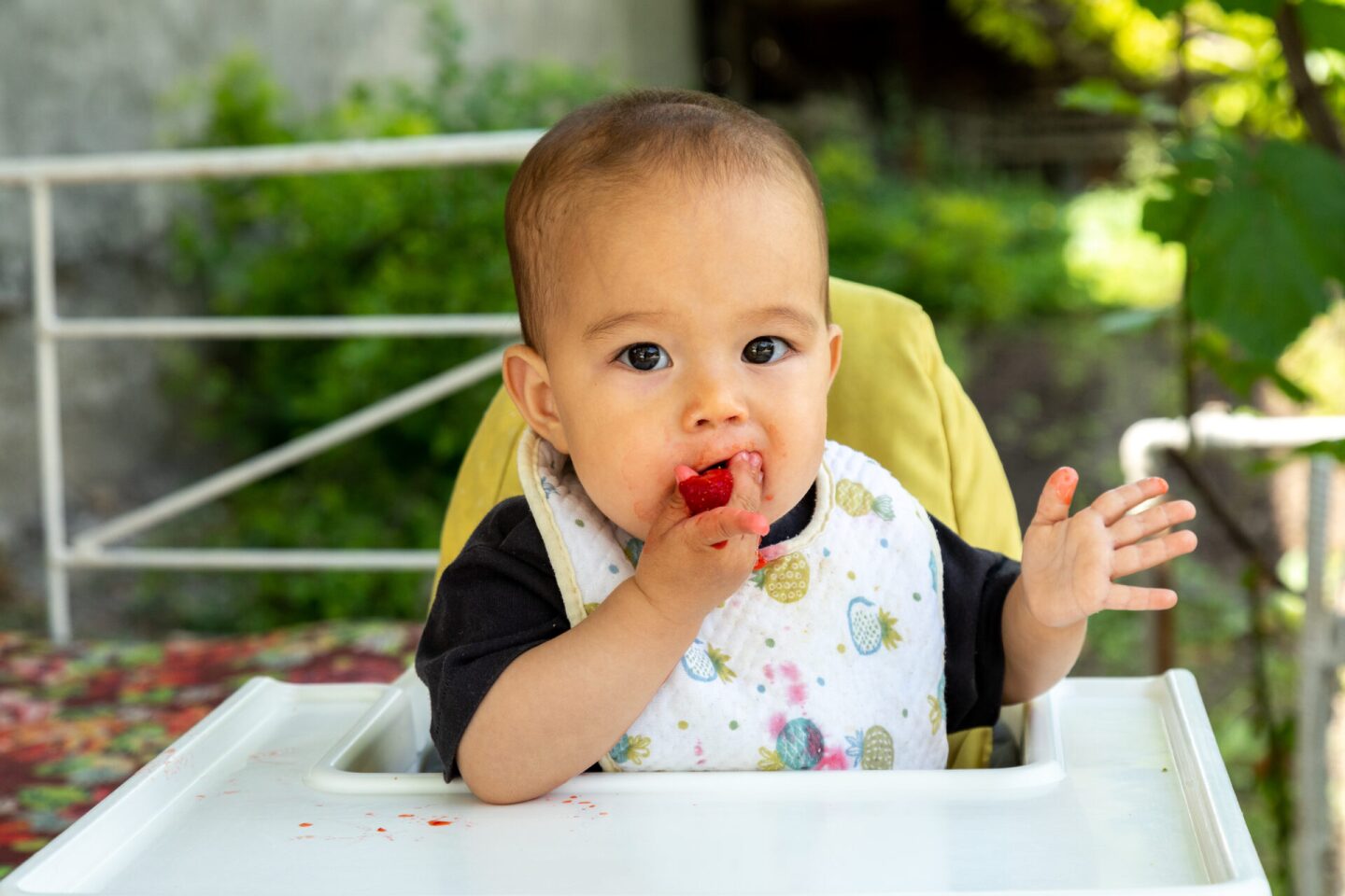 Closeup of baby eating strawberry and wearing bibs