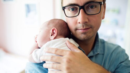 Close up of young father holding his newborn baby son