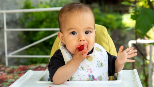 Closeup of baby eating strawberry and wearing bibs