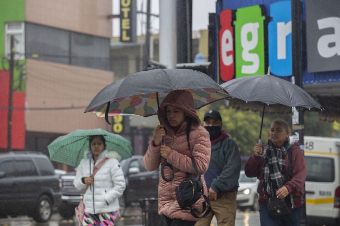 Personas cubriéndoselos de la lluvia con paraguas en la Zona Centro de Tijuana.