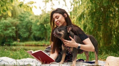 mujer lee en parque con perro