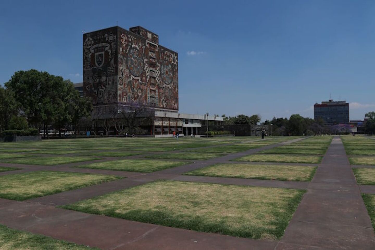 Aspectos del campus central de la UNAM donde varias áreas verdes y de esparcimiento lucen vacías tras anunciarse la suspensión de actividades académicas.
