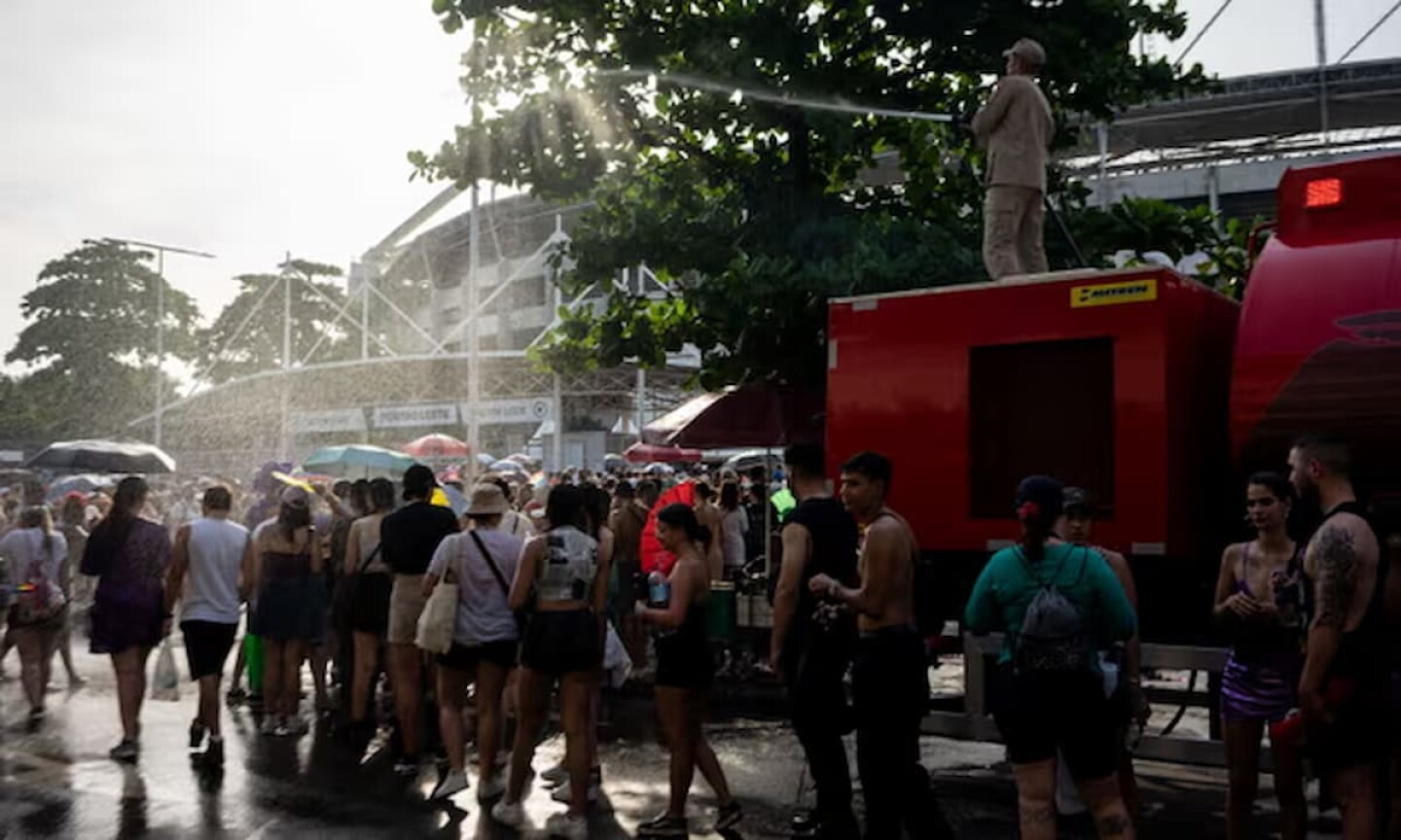 Un bombero refresca a los asistentes al concierto de Taylor Swift mientras hacen cola frente al Estadio Olímpico Nilton Santos