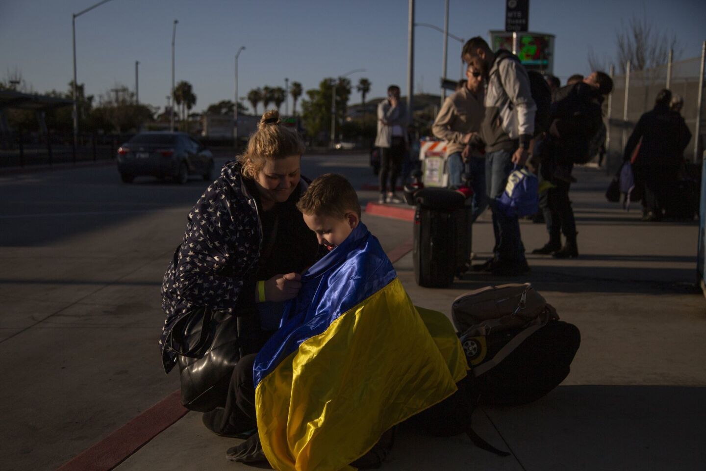 Migrantes ucranianos son recibidos por familiares en suelo estadounidense después de cruzar la frontera con México.