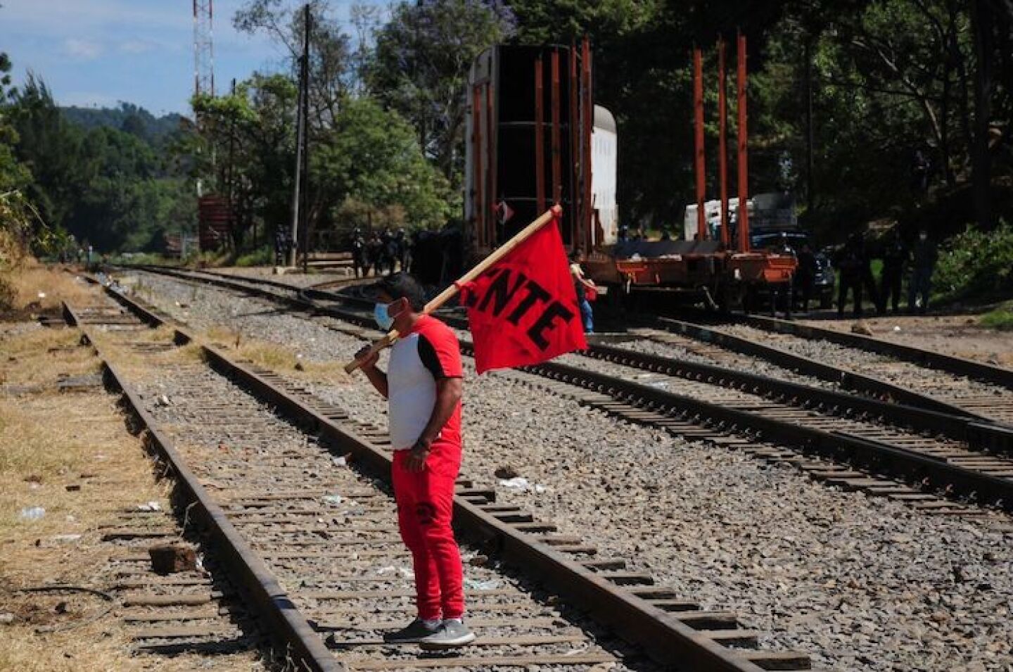 Un integrante de la CNTE pasa por el tramo de vías que era vigilado por la policía estatal.