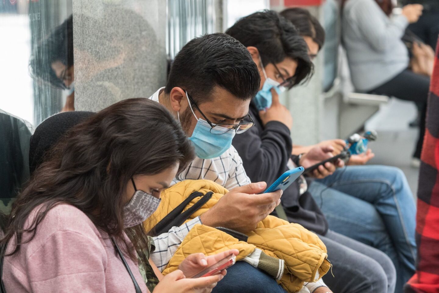 Viajantes usan su celular o teléfono inteligente en la estación Hamburgo del Metrobús.