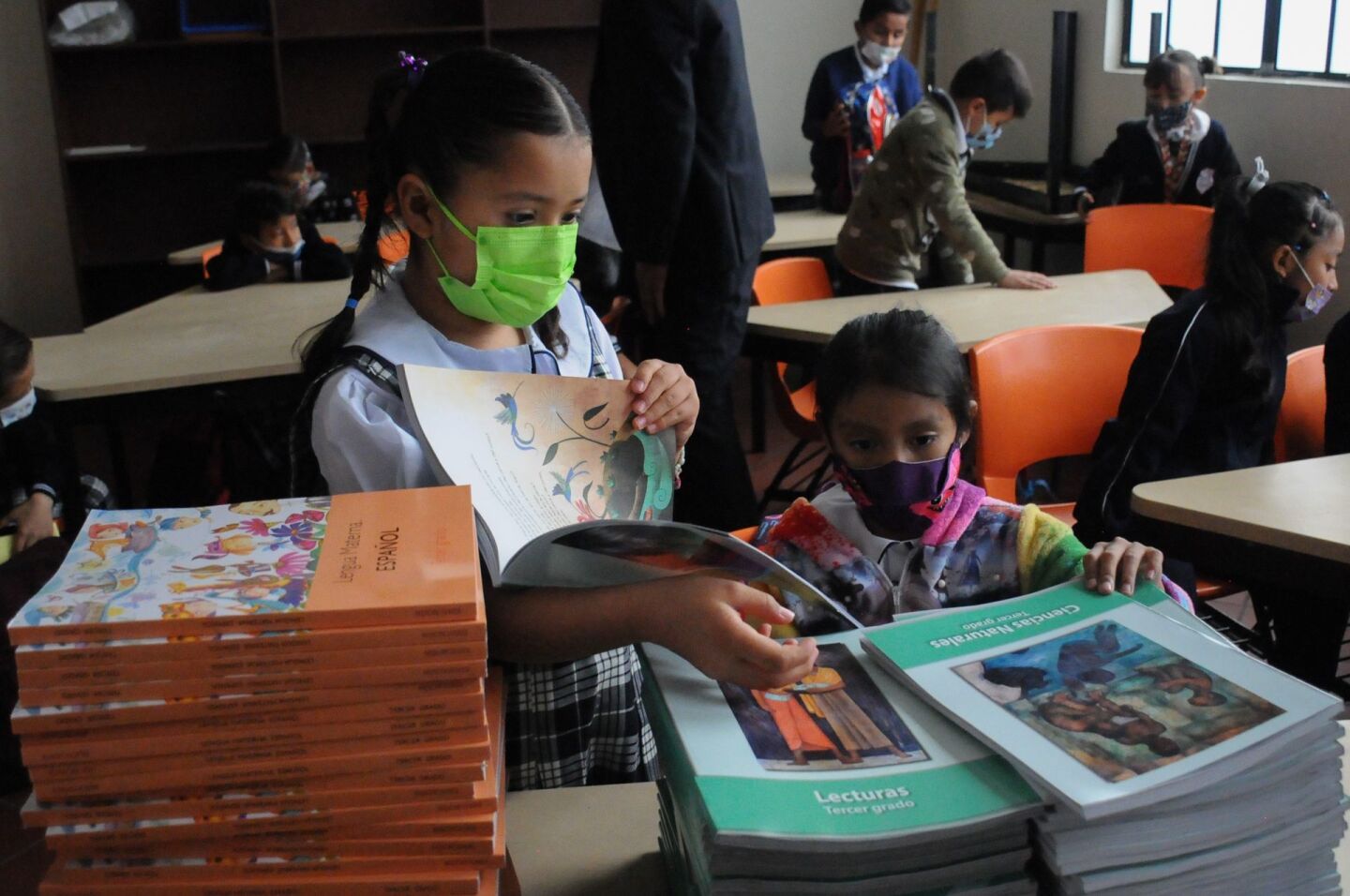 Dos alumnas revisan sus nuevos libros de texto de la SEP.