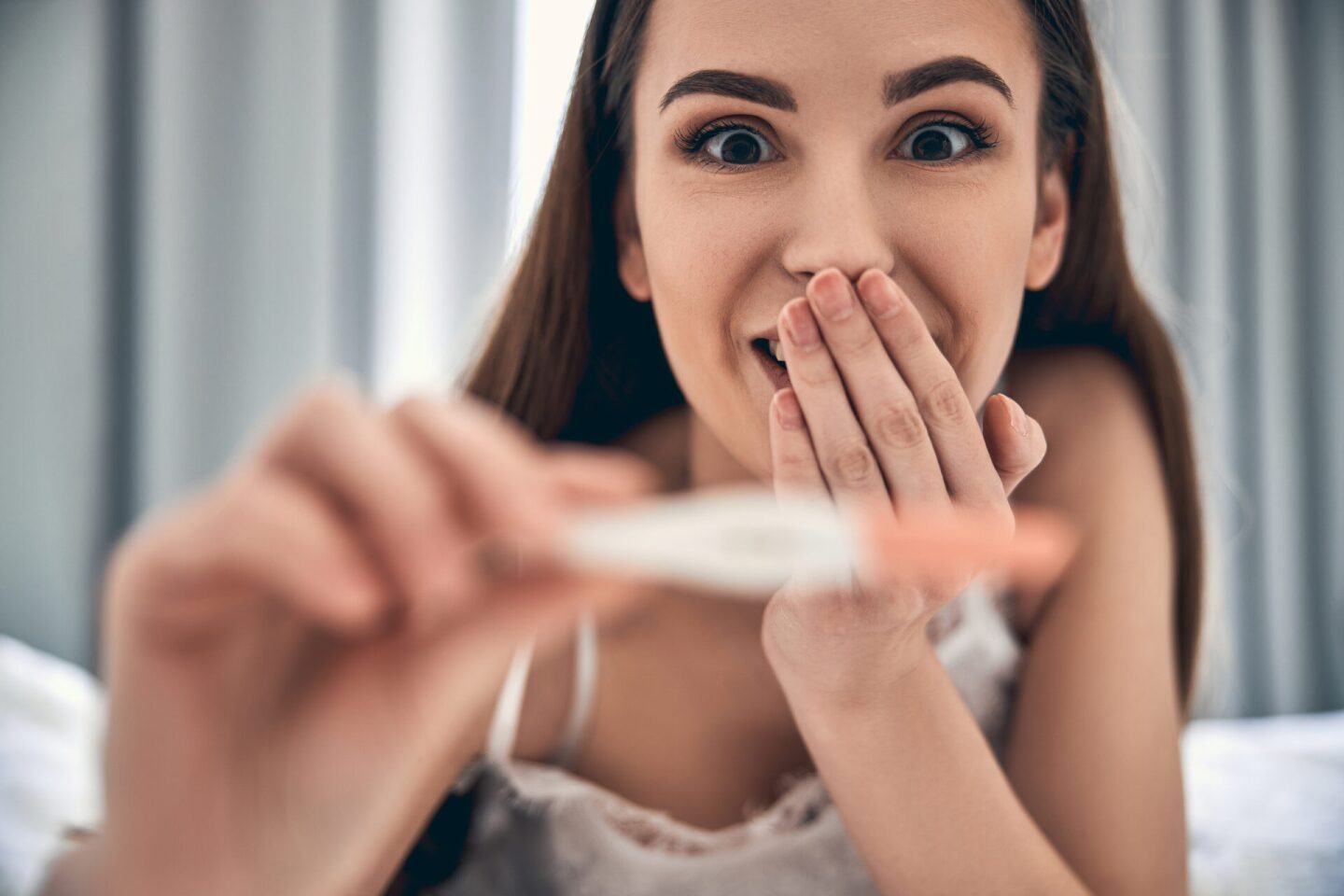 Happy young lady is showing pregnancy test