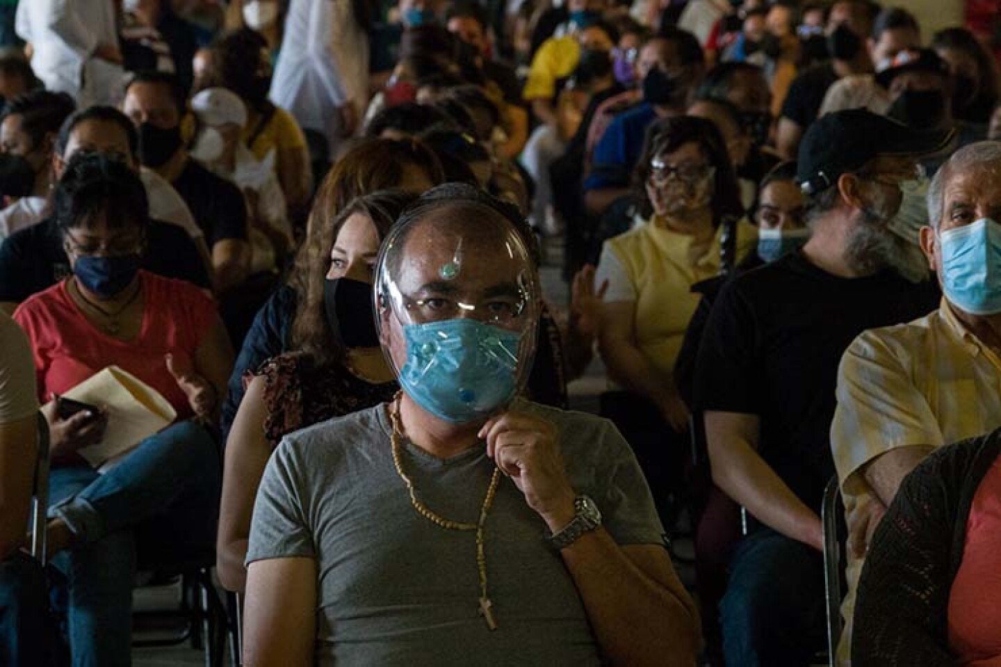 Un hombre con cubrebocas y careta, así como un rosario, permanece en la zona de observación tras ser vacunado con la dosis de AstraZeneca en Azcapotzalco.