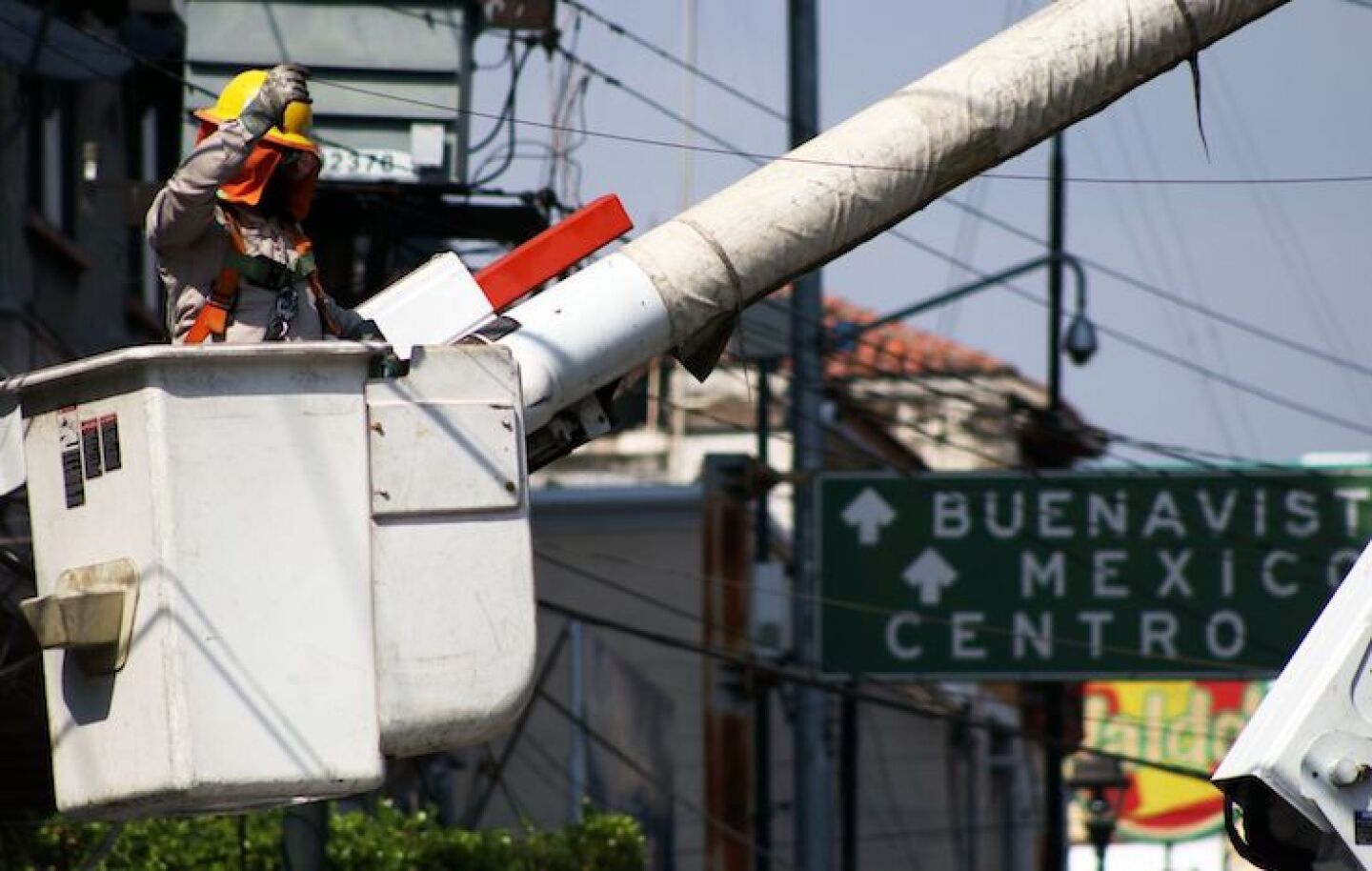 Un trabajador de la Comisión Federal de Electricidad realiza su labor en una canastilla en el centro de la ciudad.