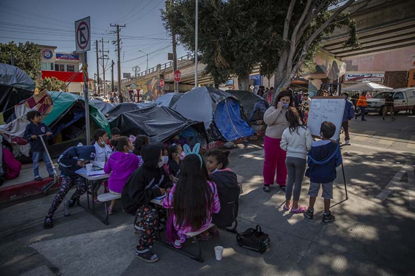 Niños migrantes reciben clase en escuela improvisada en el campamento de migrantes ubicado en la garita.