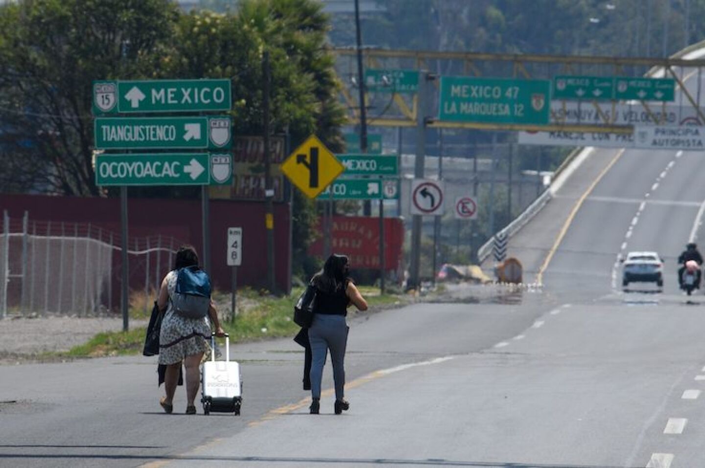 Personas que se vieron afectadas por el bloqueo de familiares de personas desaparecidas en el Estado de México en la carretera Toluca-México, optaron por caminar para llegar a sus destinos, algunos jalando maletas ya que tenían que viajar.