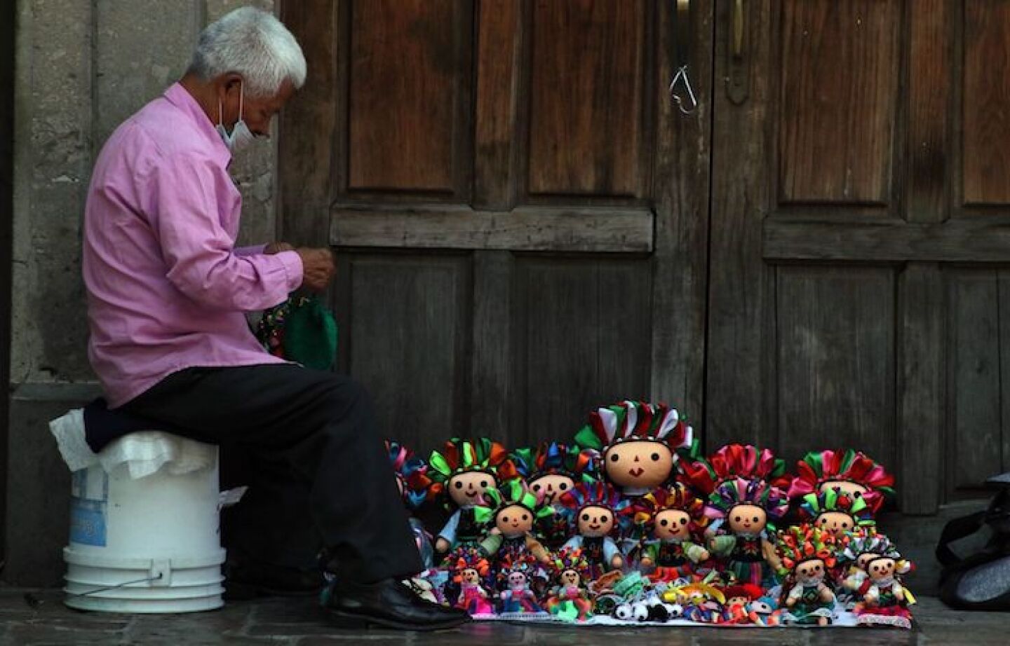 Un hombre vende muñecas otomíes en el centro de la ciudad.