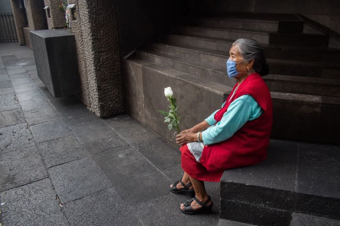 Una mujer de la tercera edad con una rosa espera a sus familiares en la Basílica de Guadalupe