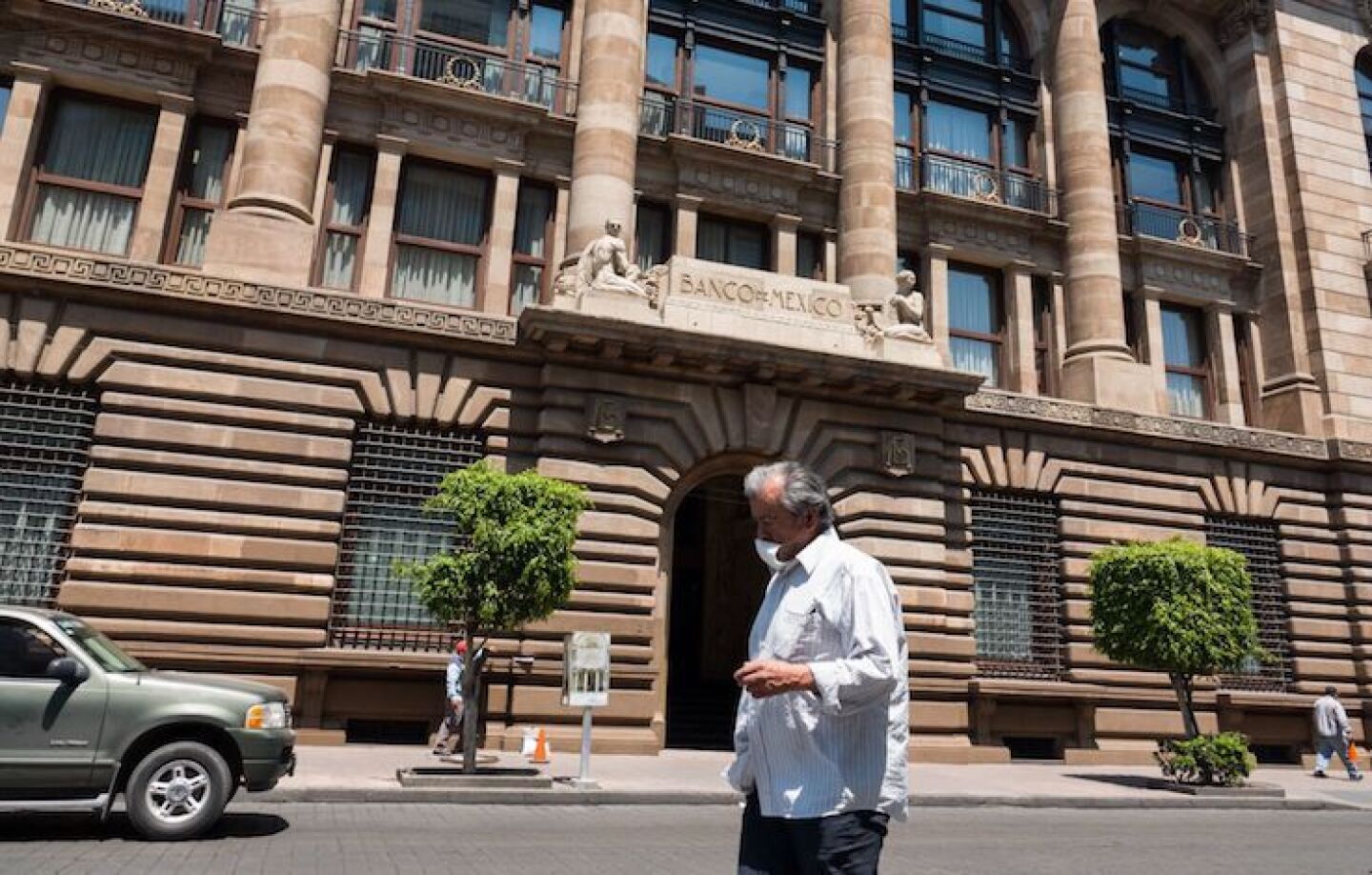 Un hombre pasa con un cubreboca por el edificio del Banco de México