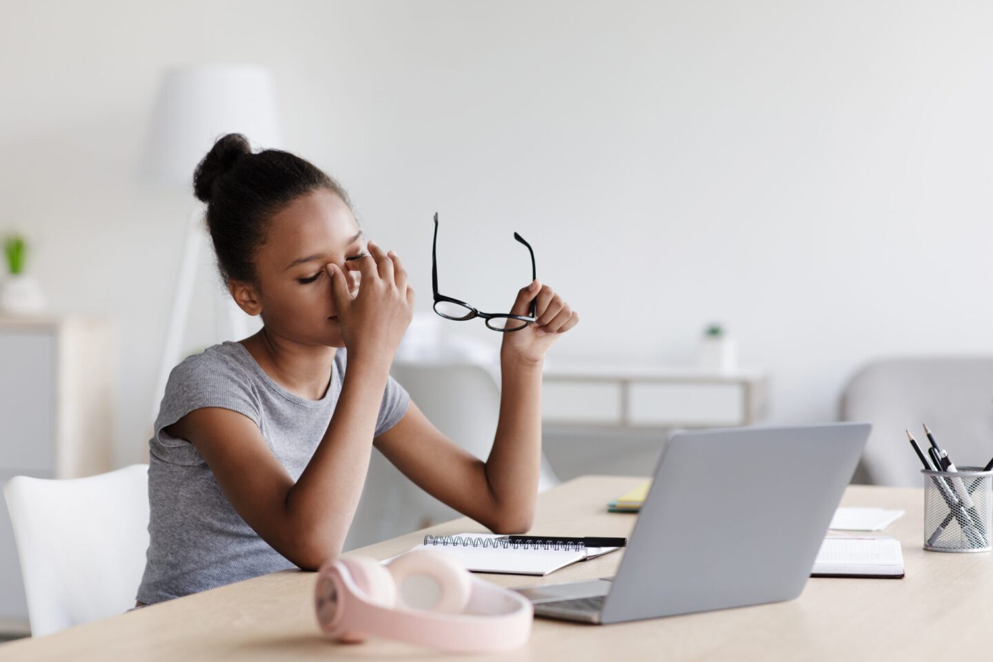Tired bored smart young african american girl takes off glasses, rests from study remotely and video lesson