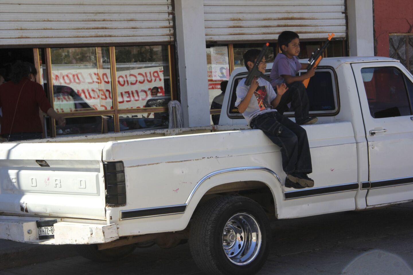 TRANCOSO, ZACATECAS, 12FEBRERO2013.- Como si fueran sicarios, policías , o soldados, niños se pasean en la caja de la camioneta de su papá portando dos armas de juguete y simulando que disparan a la gente o al aire. Esto en la fiesta patronal de ese municipio, donde el día de hoy, desfilan por las calles danzas y gente en honor a la virgen de Guadalupe. FOTO: ALEJANDRO ORTEGA NERI /CUARTOSCURO.COM