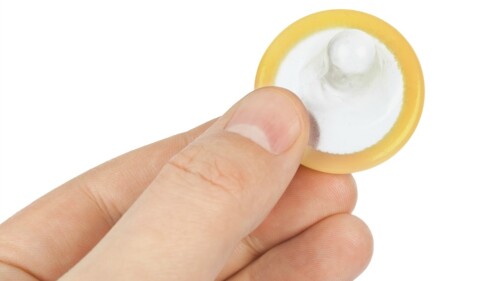 Condom in hand isolated on white background