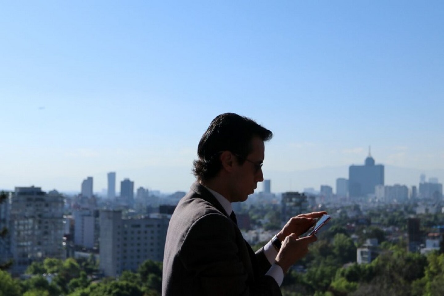 Un capitalino observa su celular desde el Castillo de Chapultepec.