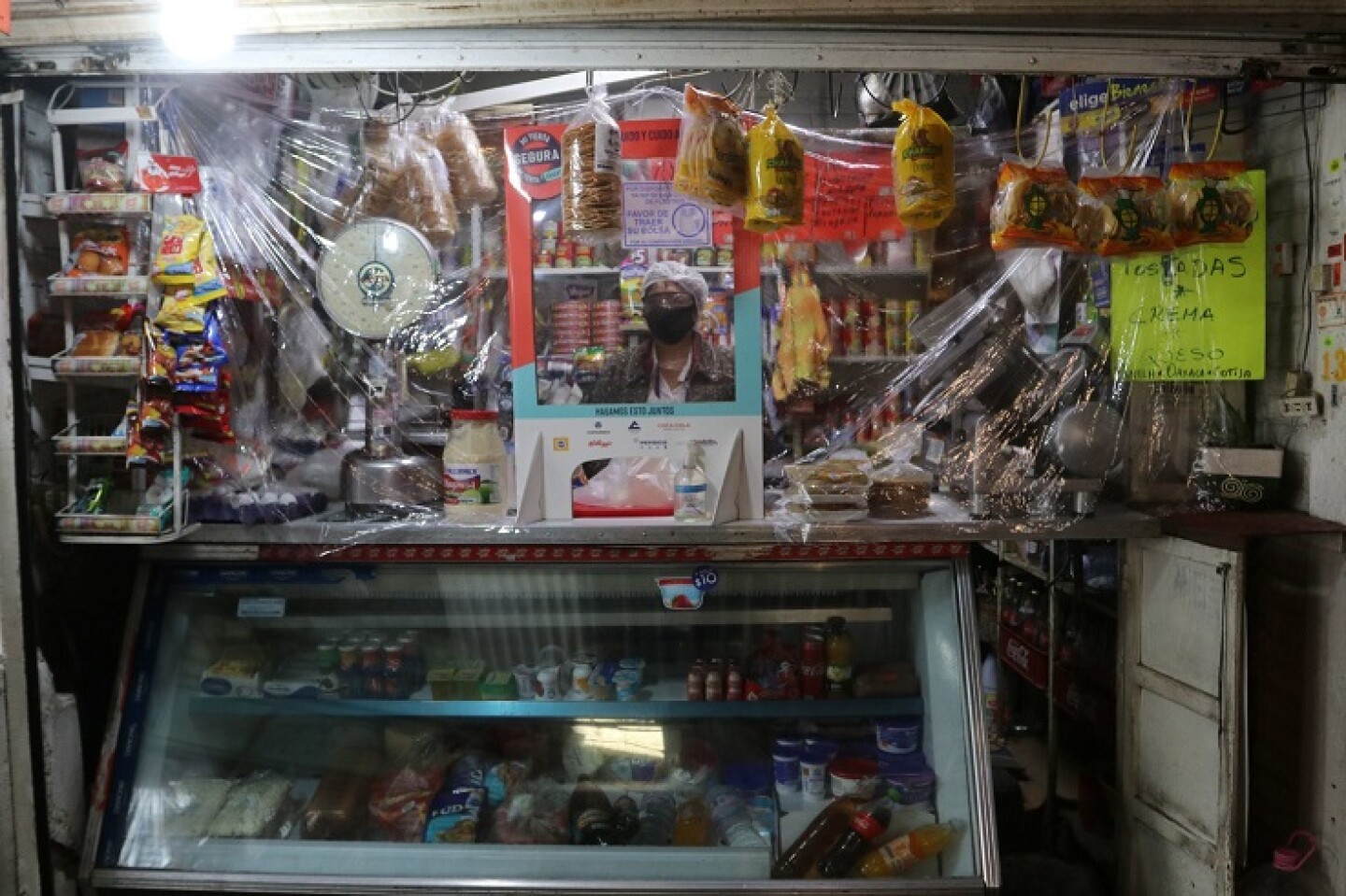 Una comerciante utiliza cubrebocas e instaló en su tienda de abarrotes hule cristal como medidas de prevención del contagio del Covid-19 en la alcaldía Iztapalapa