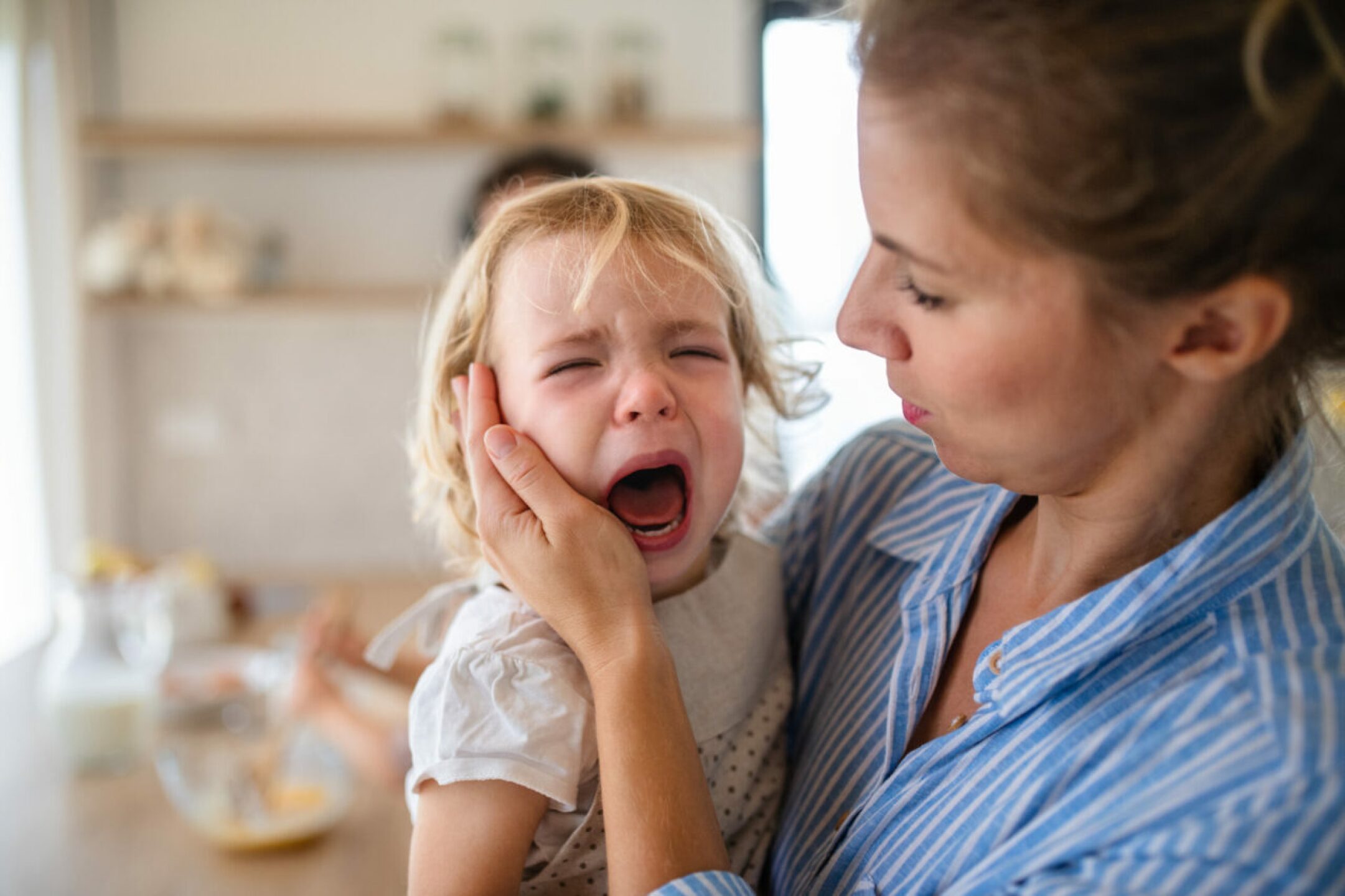 a-mother-holding-a-crying-toddler-daughter-indoors-2021-08-27-17-56-06-utc-1280x853