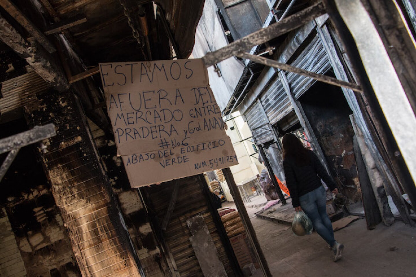 Mujer camina por los pasillos de los locales del Mercado de la Merced afectados por el incendio