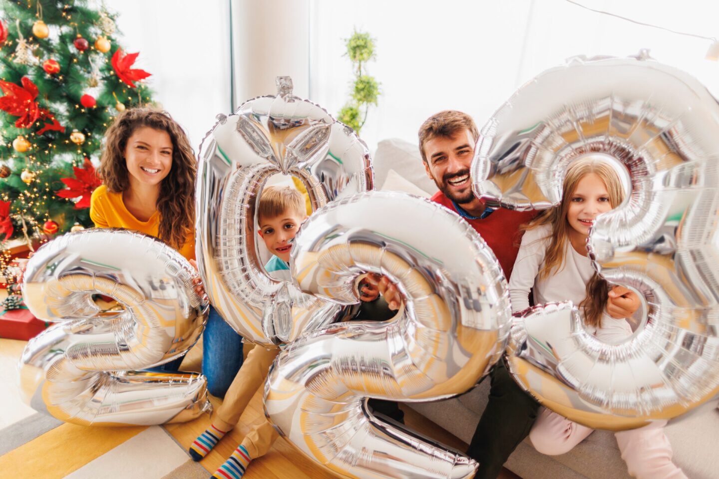 Family holding giant balloons shaped as numbers 2023 representin