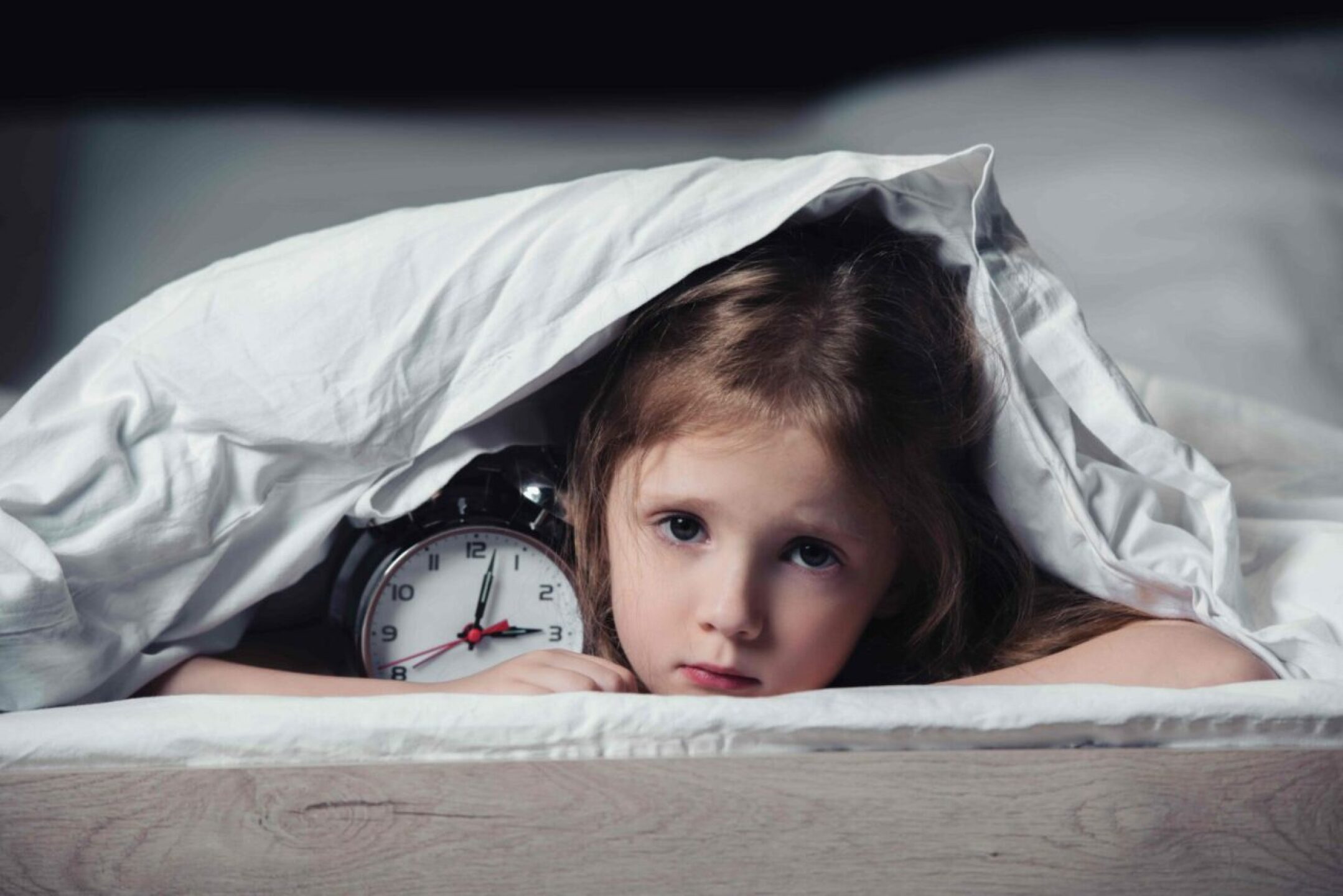 scared-kid-hiding-under-blanket-with-alarm-clock-a-2022-12-16-16-25-58-utc-1-1280x854