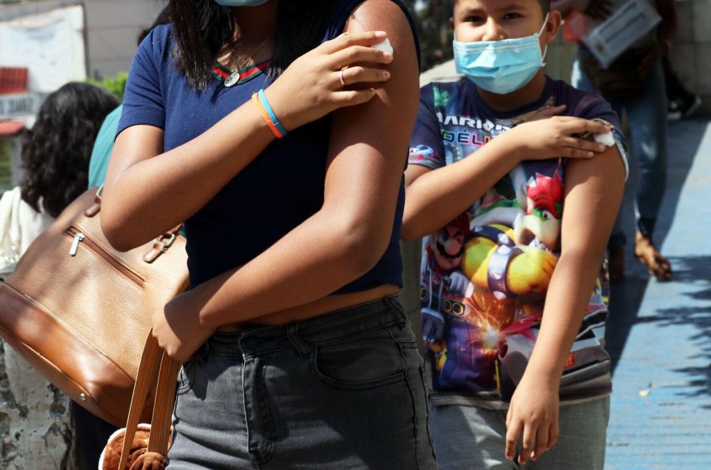 Dos menores de edad salen de la clinica 20 del IMSS donde se les aplico la vacuna Pfizer contra el Covid-19.