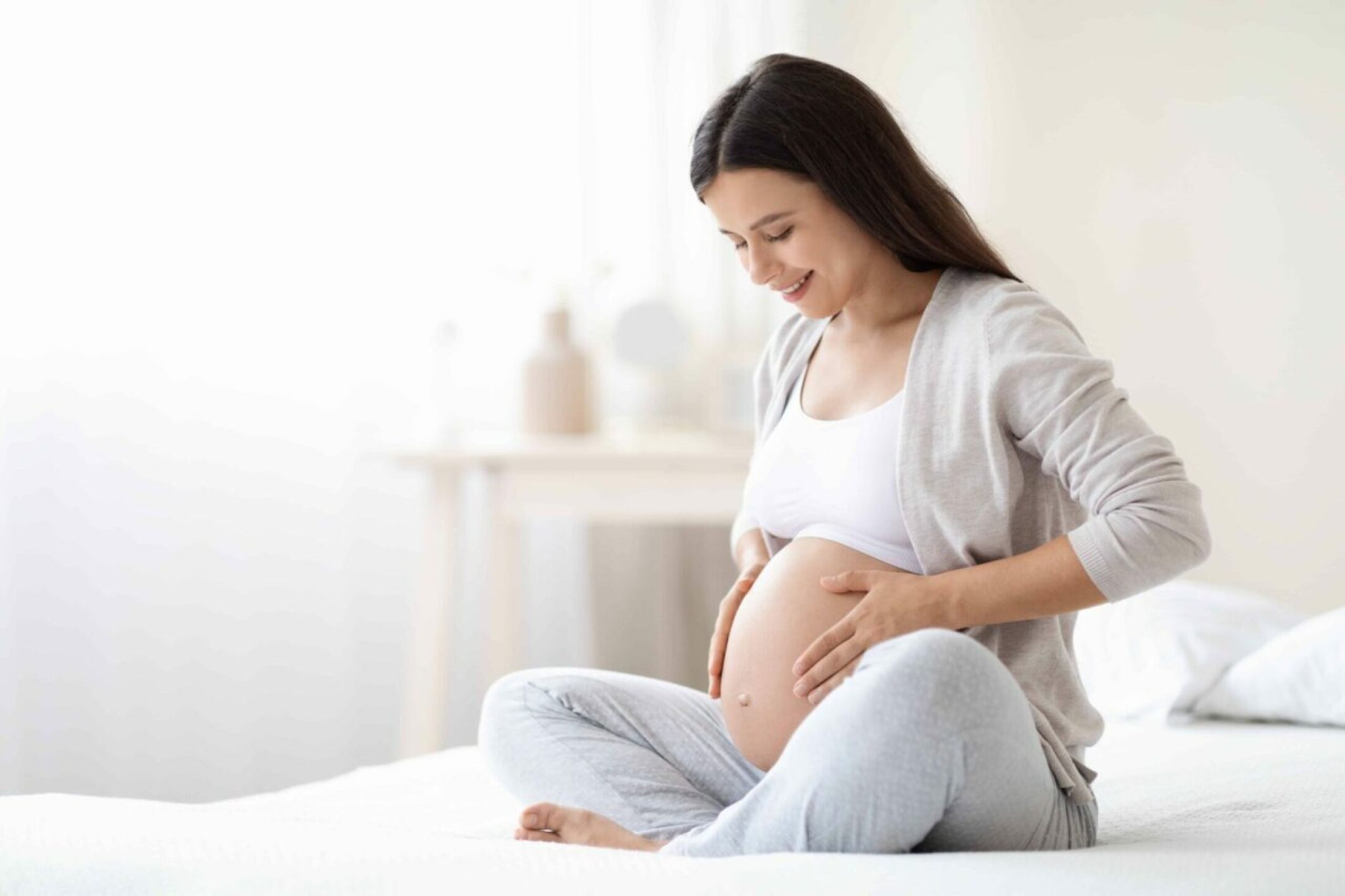 smiling-pregnant-woman-sitting-on-bed-in-her-bedro-2022-12-16-08-45-19-utc-1-1280x853