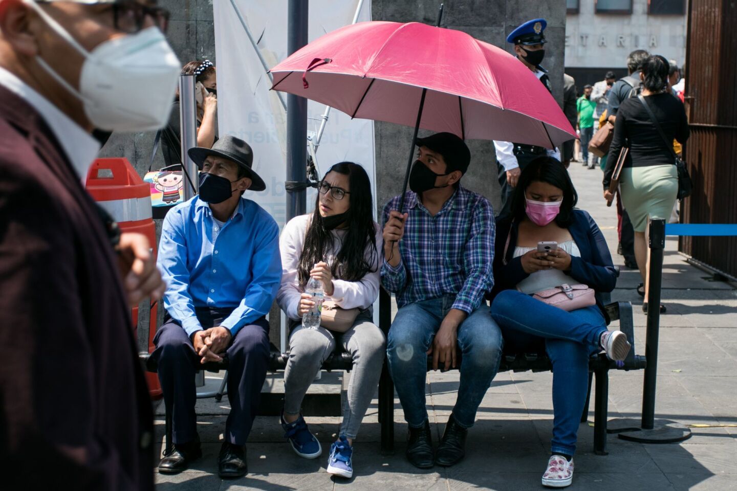 Una sombrilla es compartida por tres jóvenes y un señor en los juzgados de avenida Juárez.